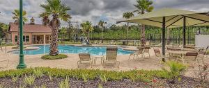 un patio avec des chaises et un parasol à côté d'une piscine dans l'établissement Lakefront Luxury Retreat 5BR, à Jacksonville