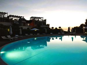 a large blue swimming pool with the sun setting at Silver horn apartment in Pizzo