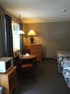 ein Hotelzimmer mit einem Bett und einem Schreibtisch mit einer Mikrowelle in der Unterkunft Z Bar Motel in Buffalo