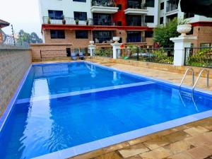 a pool with blue water in front of a building at modern executive three bedroom apartment which features a swimming pool, state of the art fully equipped gym and all modern unmatched luxurious facilities which offfers luxury lifestyle in Nairobi