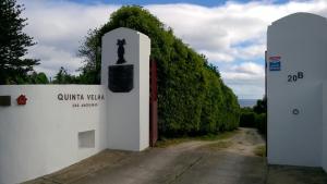 un muro bianco con una porta con una statua sopra. di QVA - Quinta Velha das Amoreiras a Vila Franca do Campo