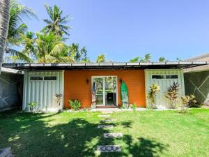 an orange house with a grass yard in front of it at Tropical 2BR Escape & Walk to Selong Belanak Beach in Selong Belanak