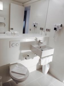 a white bathroom with a sink and a toilet at Hotel Pavillon des Gatines in Plaisir