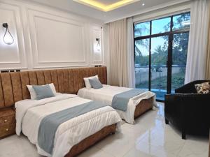 a bedroom with two beds and a couch and a window at Serian Breeze Villa in Ukunda