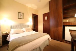 een slaapkamer met een groot bed en een open haard bij Europa Hotel in Campos do Jordão