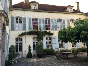 un edificio con persianas azules y una mesa frente a él en B&B Le Jardin de Carco, en Châtillon-sur-Seine