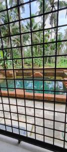a view through a glass window with palm trees at Traditional Kerala house, Kannur-Thalassery in Tellicherry