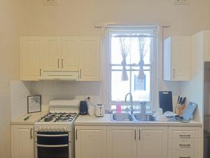 Una cocina con estufa, fregadero y ventana. en Affordable Queen Room in Earlwood - EW5, en Sídney