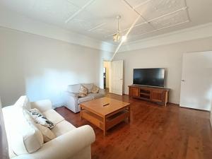 Una sala de estar con un sofá blanco y un televisor. en Affordable Queen Room in Earlwood - EW5, en Sídney