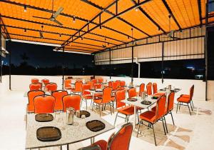 a dining room with tables and chairs and orange chairs at Starlight Hotels T-Nagar in Chennai