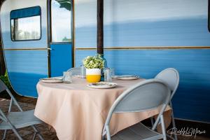 a table with a pink table cloth and chairs and a blue trailer at Raapfontein Self-Catering and Camping in Hanover