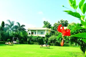 Un resort con dos personas sentadas en bancos en un parque. en Motibagh Resort, en Sawāi Mādhopur