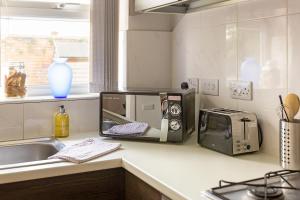 a kitchen counter with a toaster oven and a microwave at Large Ground Floor Pet Friendly 2 Bedroom Apartment with FREE Parking in Loughborough