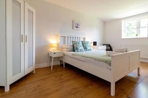 a white bedroom with a bed and a window at Large Ground Floor Pet Friendly 2 Bedroom Apartment with FREE Parking in Loughborough