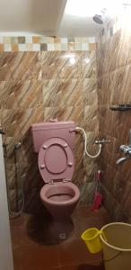 a pink toilet in a bathroom with a shower at White Villa Guest House in Puducherry