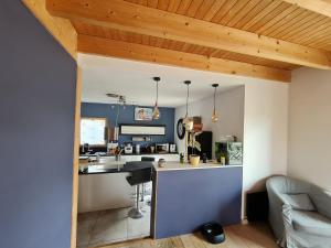 a kitchen with blue walls and a wooden ceiling at Belle Maison bois avec piscine proche de la plage in Landéda