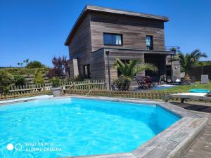 a house with a swimming pool in front of a house at Belle Maison bois avec piscine proche de la plage in Landéda