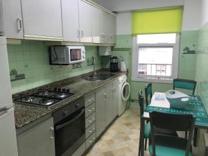 a kitchen with a stove and a sink and a table at Apartamento cerca de la playa in Viveiro
