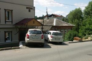 dos autos estacionados en un estacionamiento al lado de un edificio en Studios on Grazhdanskaya, en Vladimir