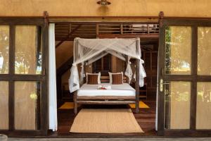 a bed with a canopy in a room with windows at Villa zakitoo in Sainte Marie