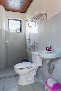 a white bathroom with a toilet and a sink at Aroha Hostel in Coron