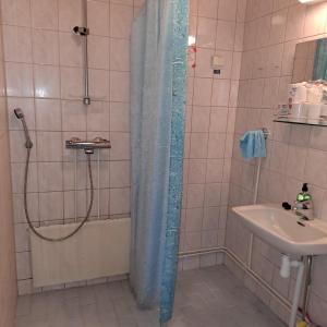 a shower with a blue shower curtain next to a sink at Karhunkierros Apartment in Hautajärvi