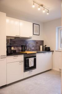 a kitchen with white cabinets and a sink at Gemütlich wohnen im Herzen des Hunsrücks in Emmelshausen