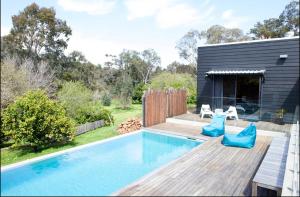 a swimming pool with a wooden deck next to a house at Quenda Guesthouse in Hovea