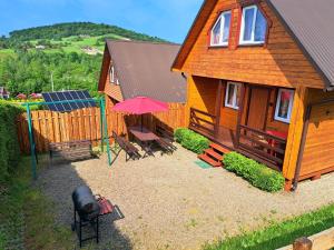 a house with a playground and a house with a table and umbrella at Nirwana - Domki Całoroczne w Solinie in Solina