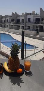 a pineapple and oranges on a plate next to a drink at Cosy Casa New penthouse in San Miguel de Salinas