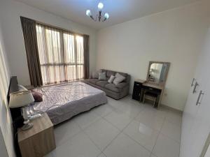 a bedroom with a bed and a couch and a mirror at Big flat 3 bedrooms, in floor 15 full service in Sharjah