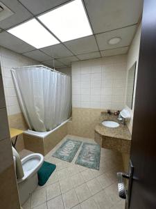 a bathroom with a toilet and a tub and a sink at Big flat 3 bedrooms, in floor 15 full service in Sharjah