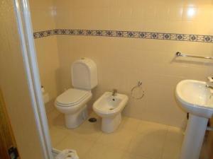 a white bathroom with a toilet and a sink at Nossa Senhora do Pranto in Ferreira do Zêzere