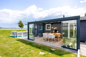 a small house with a deck and a dining room at Strandperle Lathum Ferienhaus in Premium Lage am See für Urlaub und Workation mit Hundestrand in Lathum