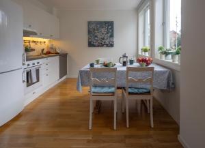 a kitchen with a table with two chairs and a kitchen with white cabinets at Ås Sentrum Suite in Ås