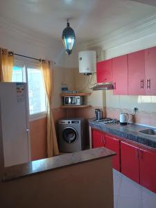 a kitchen with red cabinets and a washing machine at Appartement à usage familial in Agadir