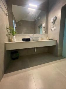 une salle de bain avec un lavabo et un grand miroir dans l'établissement Salted Shores 2BHK Beach Heritage Home, à Anjuna