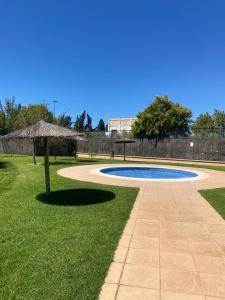 una piscina con una sombrilla en el césped en Atardeceres en Bajoguía, en Sanlúcar de Barrameda