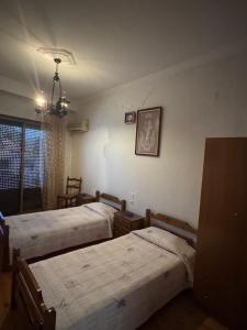 a bedroom with three beds and a chandelier at Enoikiazomena Domatia Lazaros in Dispilio