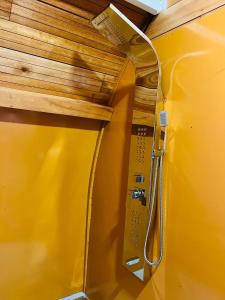 a yellow wall with a shower in a room at Garden Oasis Rekawa in Rekawa
