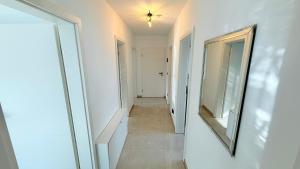 a hallway with white walls and a mirror on the wall at Himy Home - Moderne Wohnung mit große Dachterrasse in Dormagen