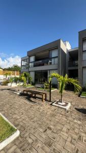 a building with a bench and palm trees in front of it at Reserva Ponta do Mutá 107 in Barra Grande