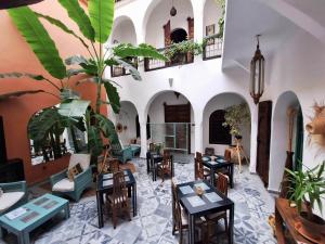 a living room with tables and chairs and a plant at Riad El Grably in Marrakesh