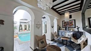 a living room with a pool and chairs and a chandelier at Riad El Grably in Marrakesh