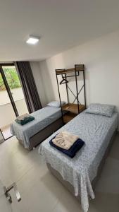 two beds in a room with a window at Reserva Ponta do Mutá 07 in Barra Grande