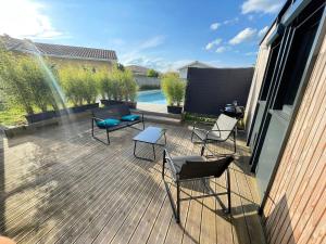 a deck with chairs and tables and a pool at la pause landaise in Saint-Vincent-de-Paul