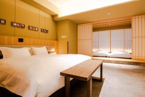 a bedroom with a large white bed and a bench at GuestHouse MIYABI Premium in Kyoto