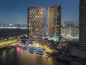 a view of a city at night with boats in the water at FIRST CLASS 1BR Waterfront Bliss in Abu Dhabi