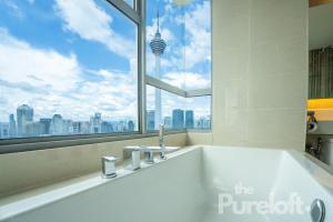 a bathroom with a bath tub with a large window at The Pureloft Suites - Bukit Bintang KLCC in Kuala Lumpur
