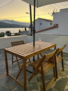 a wooden table with two chairs and an umbrella at Emma & Giannis Studios in Samos